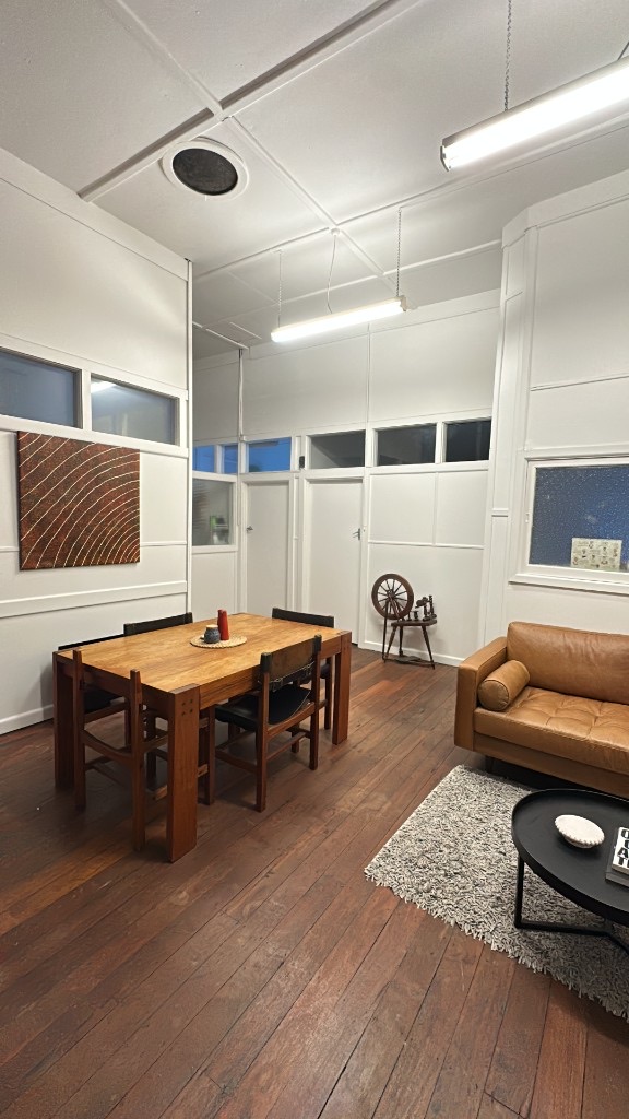 Common room with leather couch, timber dining table and high ceilings