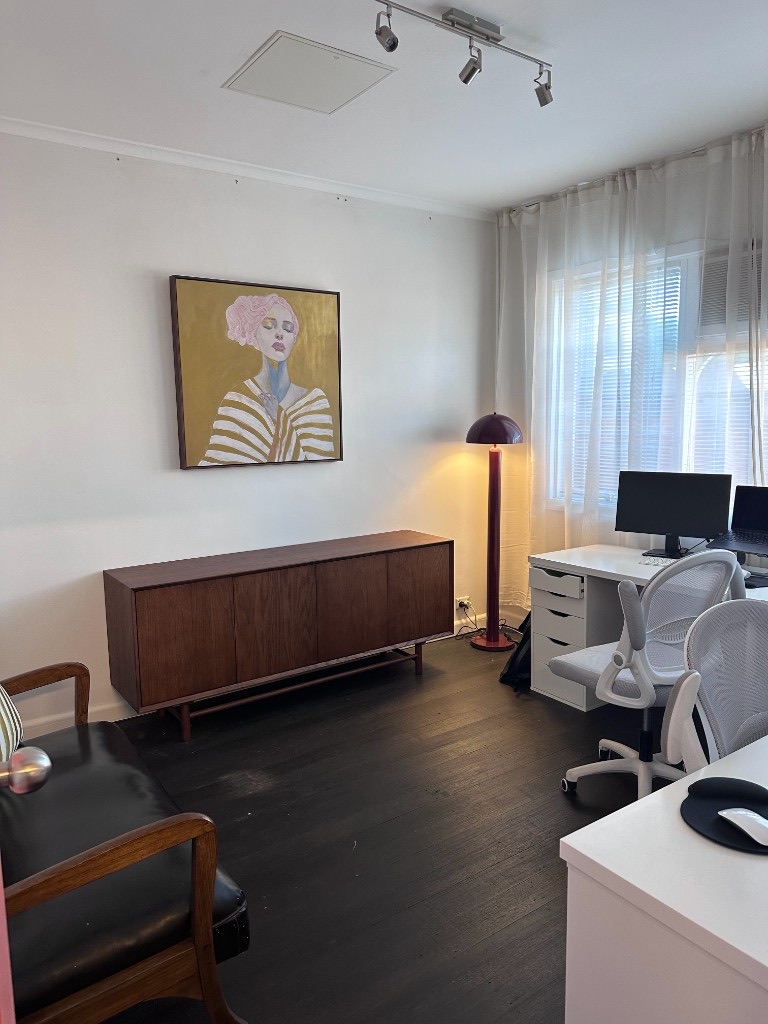Studio interior with walnut sideboard, artwork and ergonomic desk setup